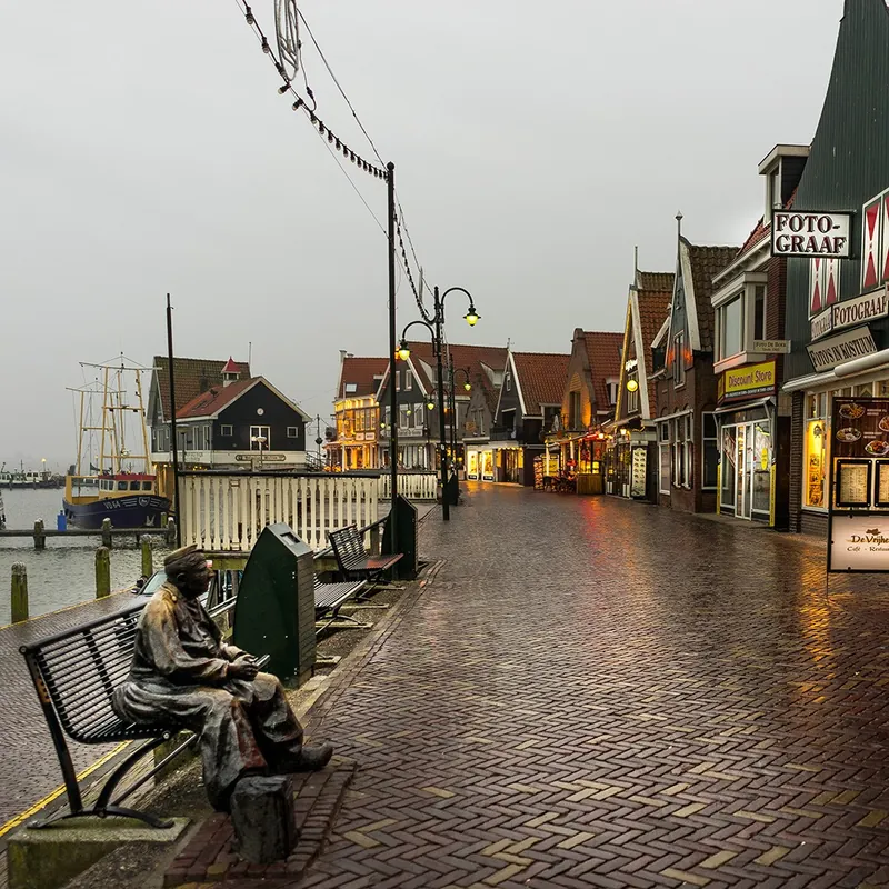 Website laten maken in Volendam De Dijk in Volendam met winkels en het standbeeld aan het water, waar SjopSjop websites maakt